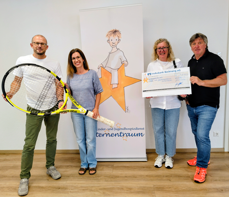 Vier Personen stehen vor einem Banner mit der Aufschrift 