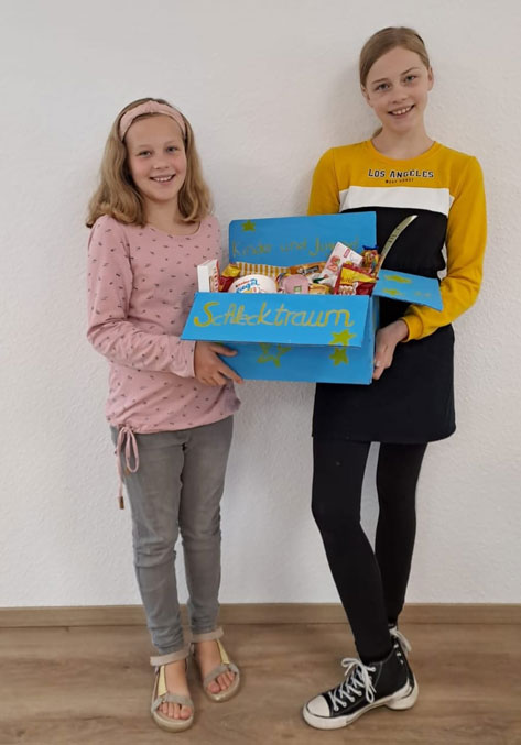 Zwei Kinder mit einer Schachtel voller Süßigkeiten
